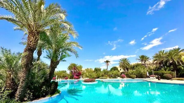 A clear blue pool surrounded by palm trees and greenery. - Magnificent T2 with swimming pool (Marrakech)