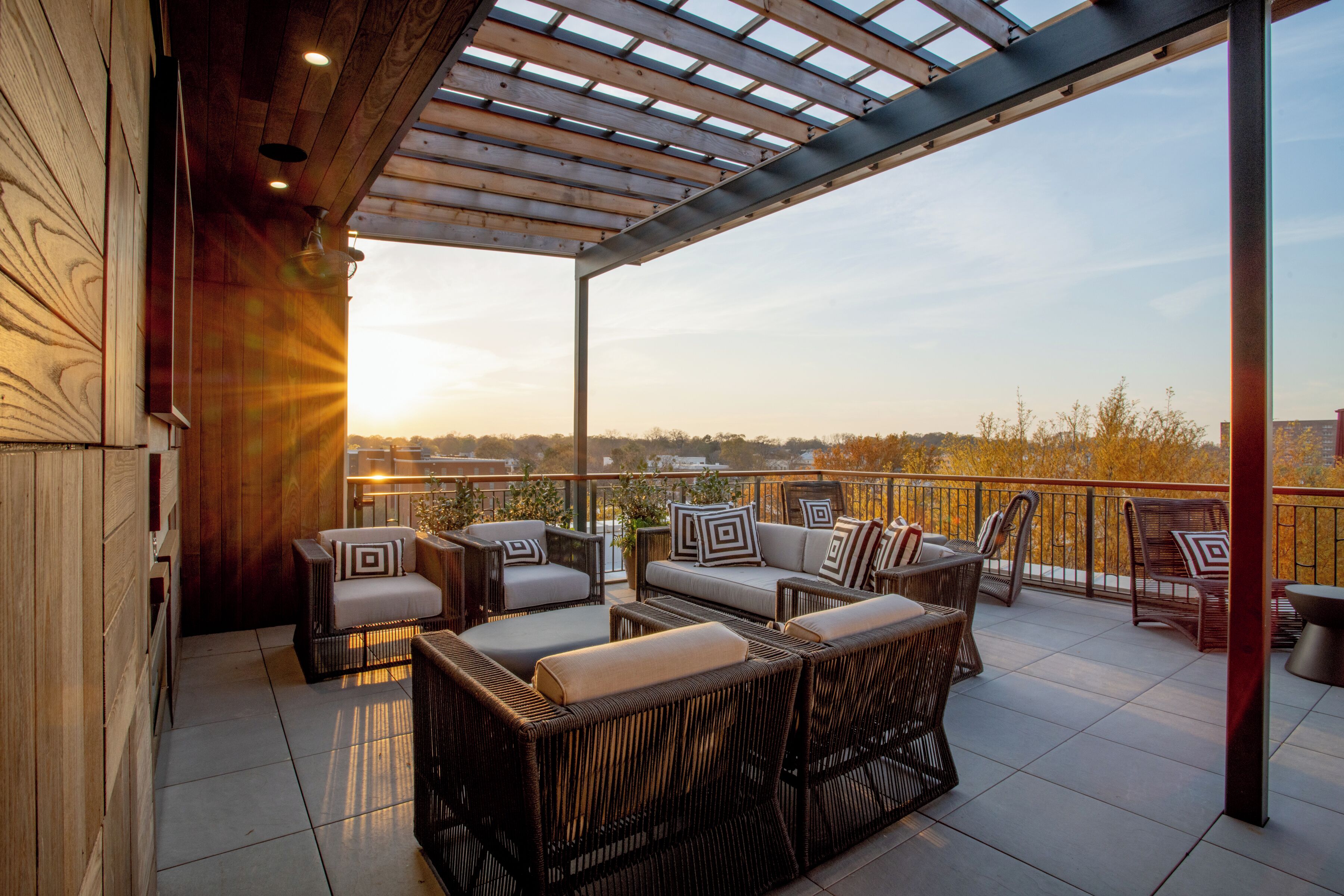 A covered outdoor seating area with wicker furniture and a view of the city skyline.