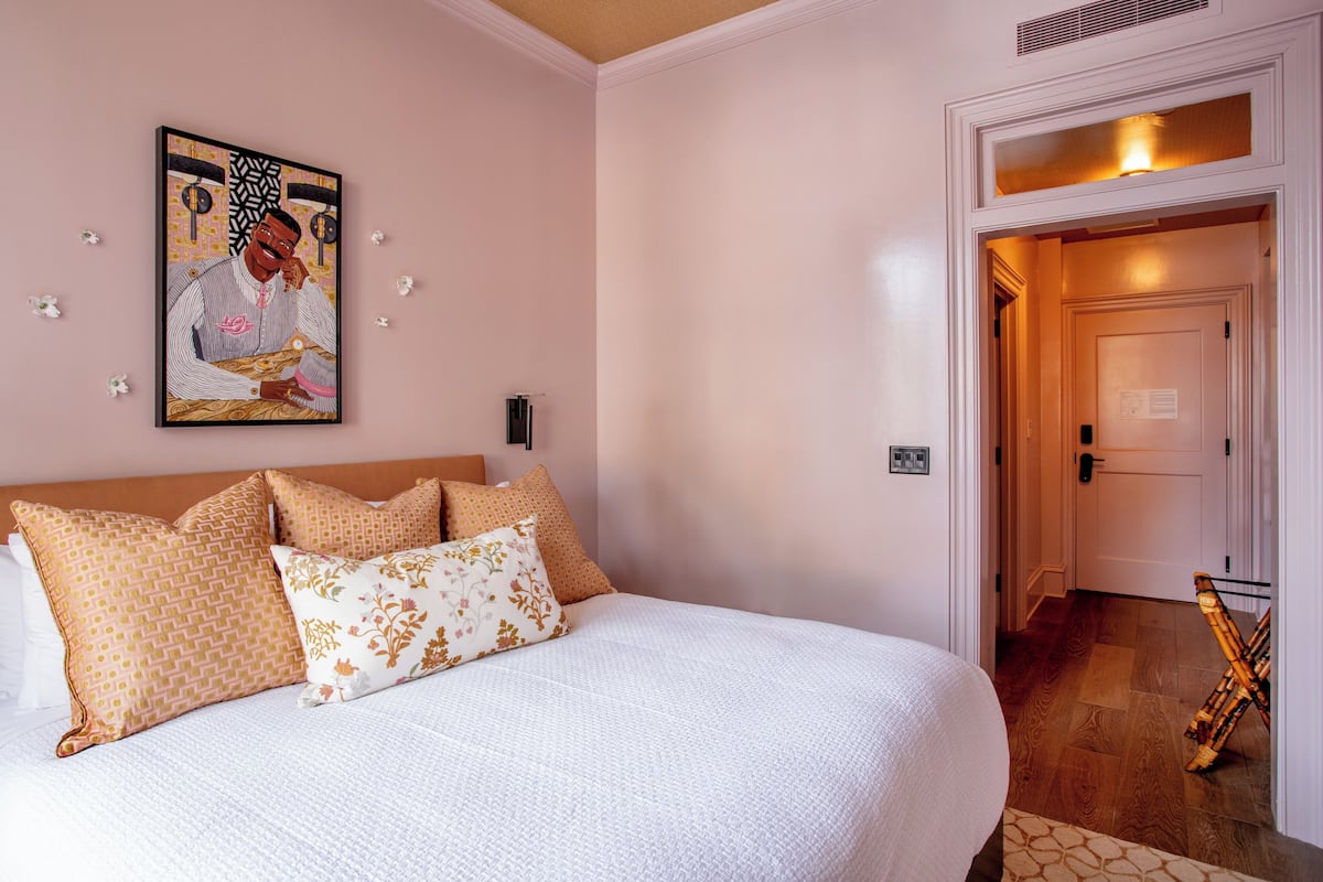 Habitación de hotel con una cama grande, cabecero y un cuadro en la pared.
