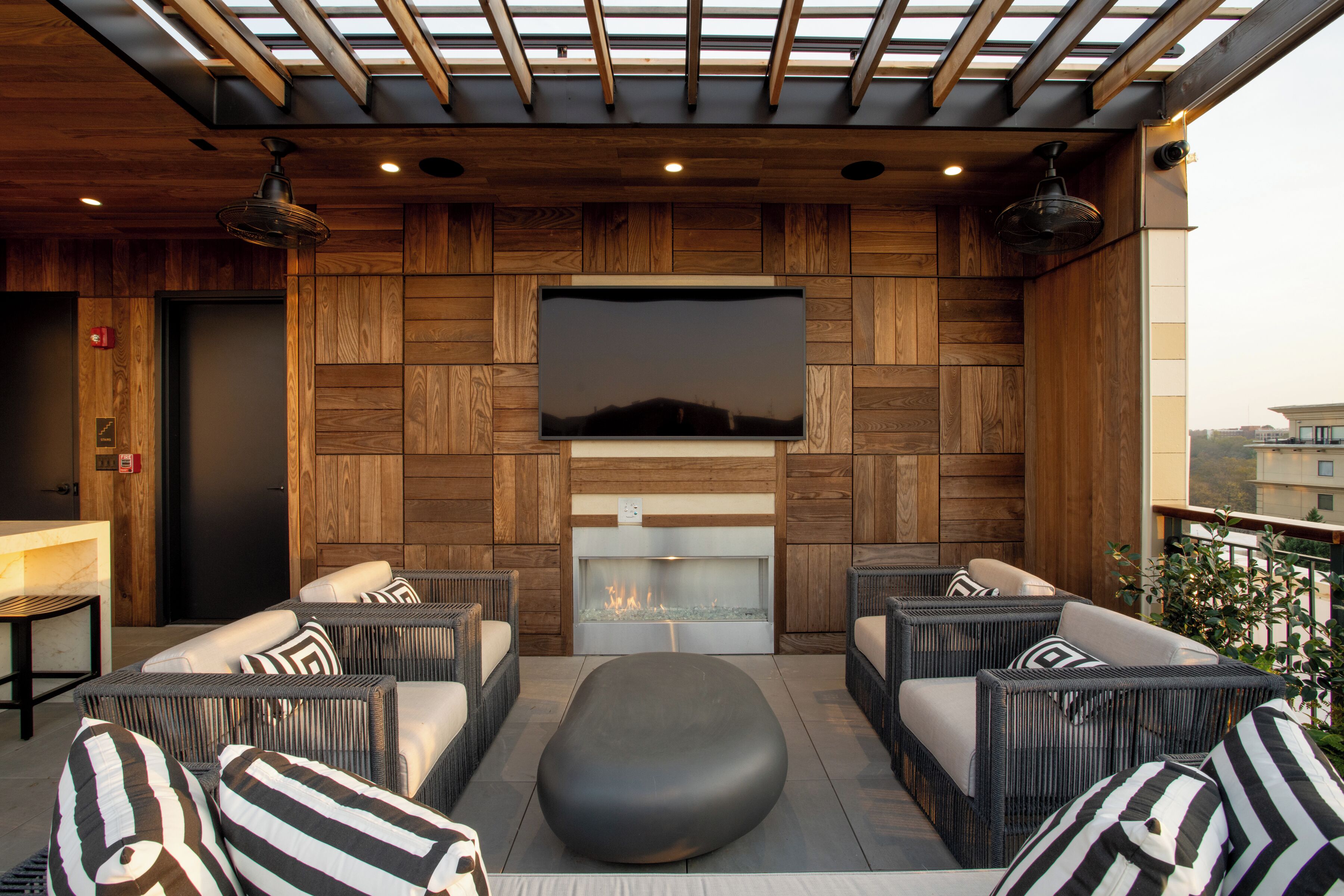 Un área de estar al aire libre acogedora con muebles de mimbre, un televisor de pantalla plana y una chimenea.