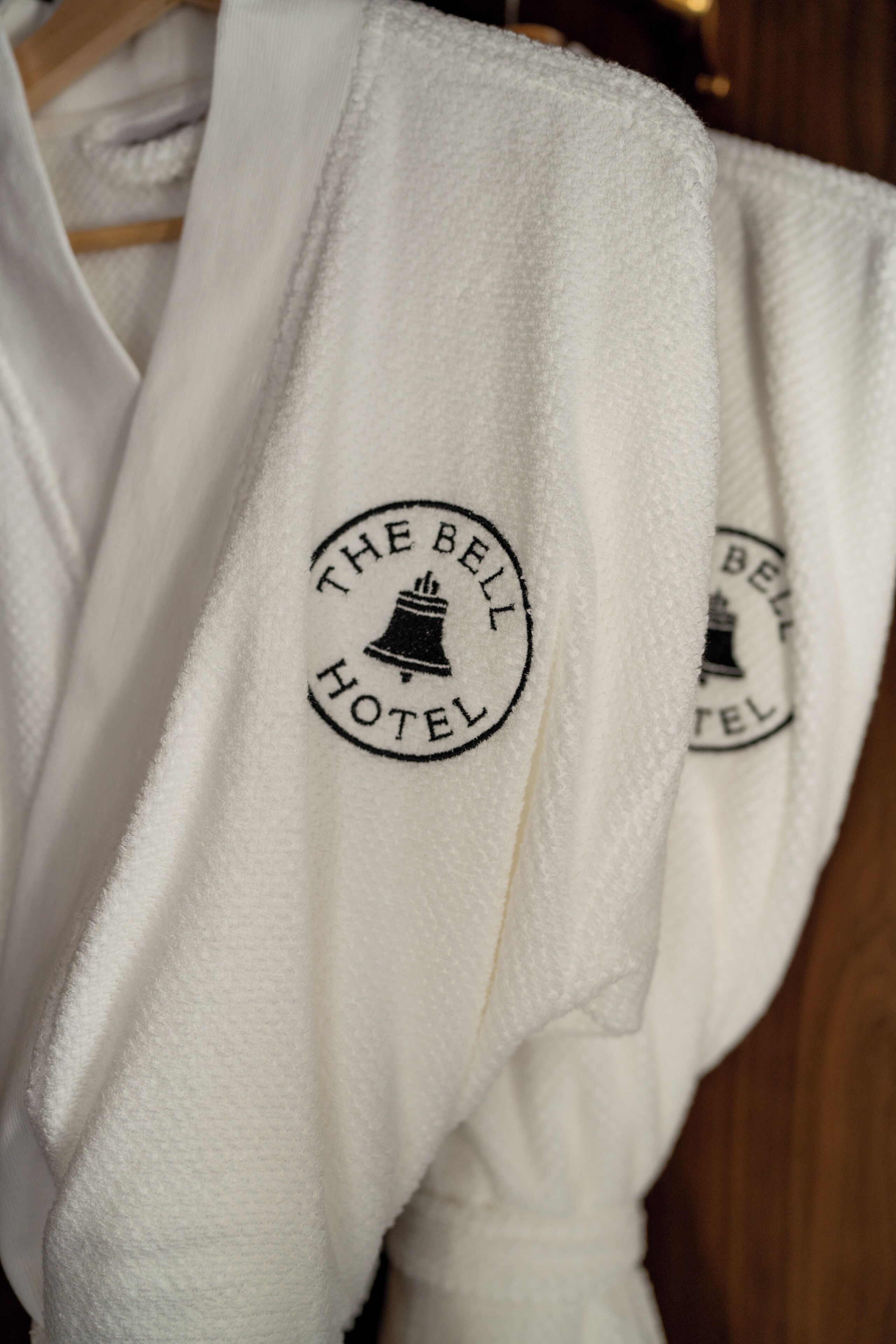 A white robe with a logo that reads "The Bell Hotel".