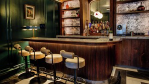 A bar area with a marble countertop, bar stools, and a wine bottle display. - The Bell Athens by Kasa Living (Athens)