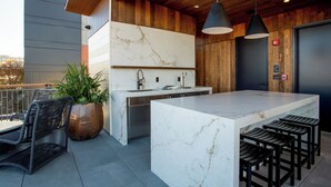 A modern kitchen with a marble countertop, wooden accents, and bar stools. - The Bell Athens by Kasa Living (Athens)