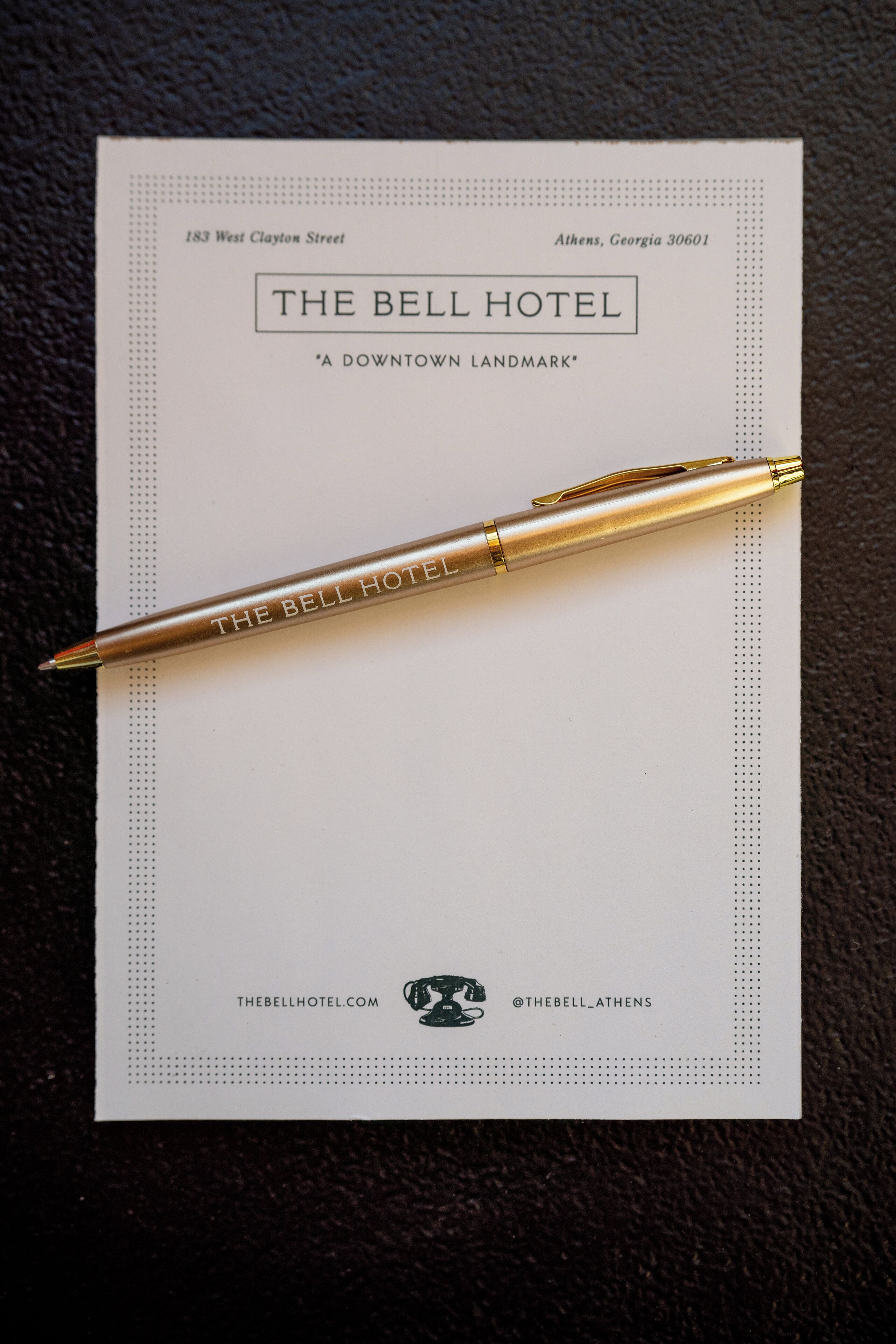 A business card for The Bell Hotel, Athens, Georgia, with a pen placed on it.