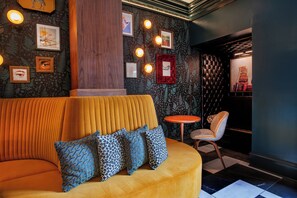 A modern interior with a curved sofa, patterned cushions, a small round table, and a chair. - The Bell Athens by Kasa Living (Athens)