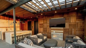A modern outdoor living area with a bar, seating, and a fireplace. - The Bell Athens by Kasa Living (Athens)