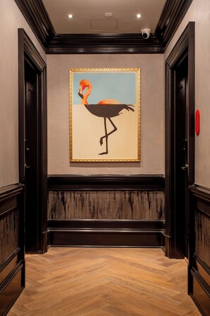 A hallway with a framed painting of a flamingo, wooden paneling, and a red object on the wall. - The Bell Athens by Kasa Living (Athens)