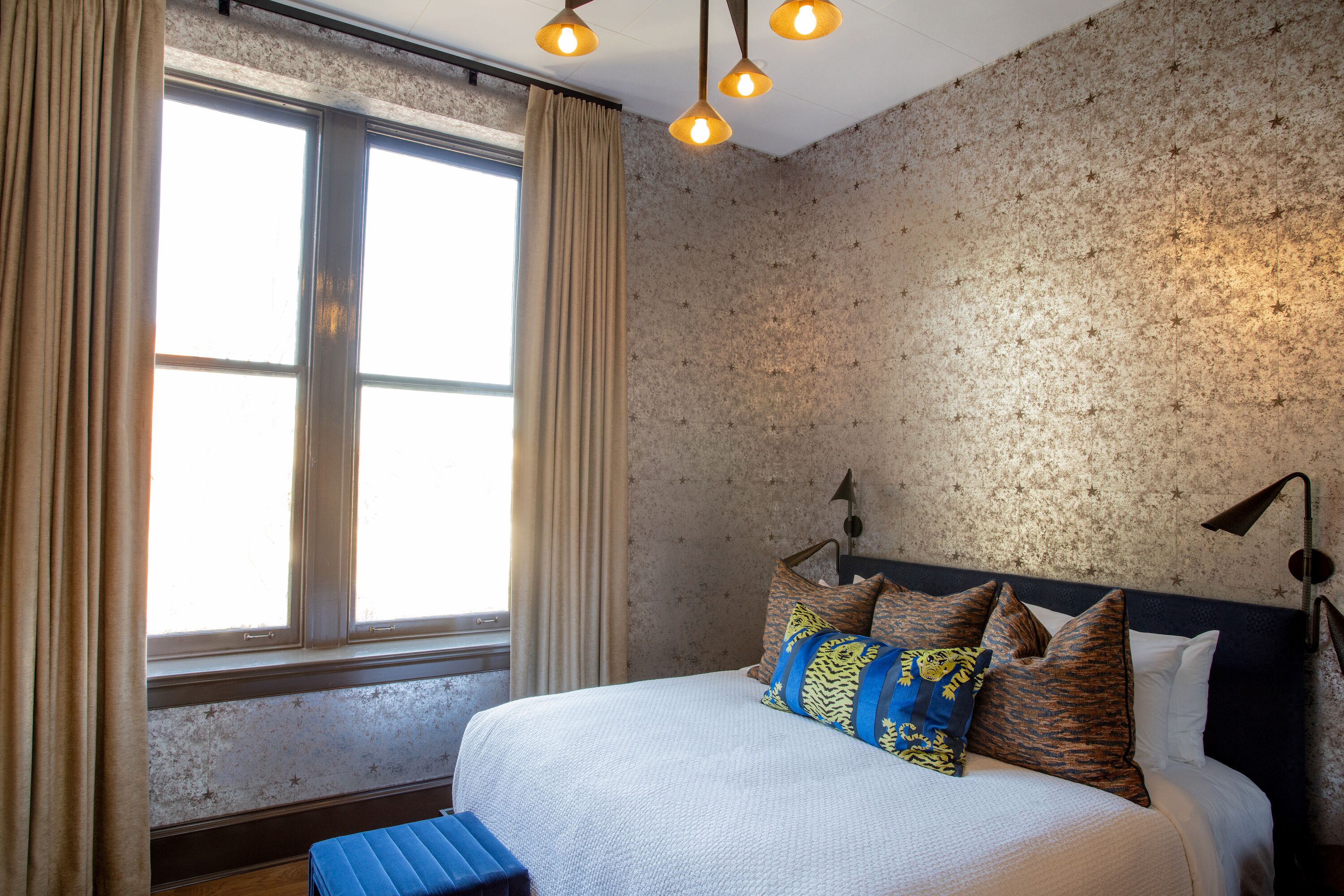 Una habitación de hotel con una cama grande, una ventana con cortinas y una pared con textura.
