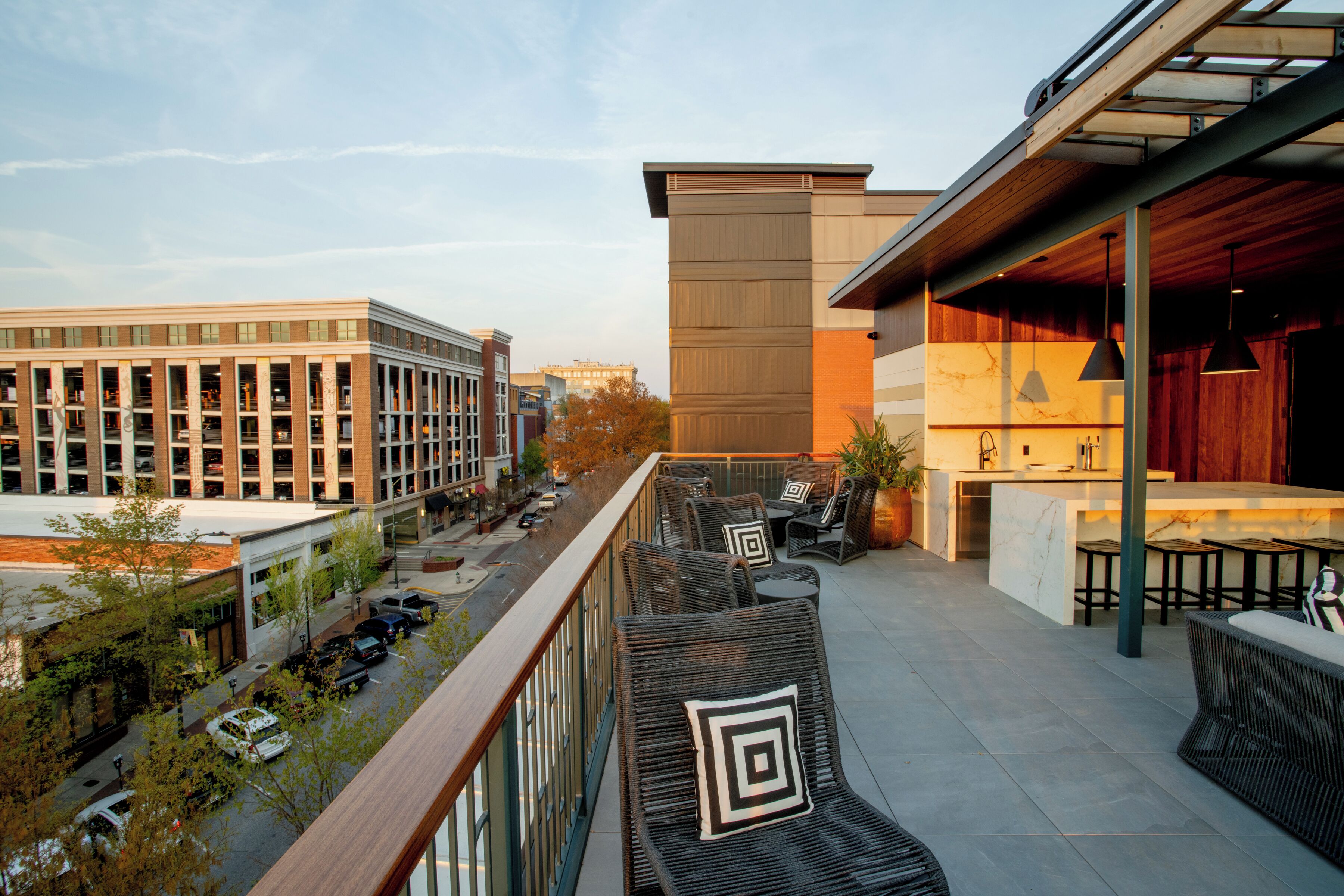 A rooftop terrace with outdoor seating, a bar area, and a view of the cityscape.