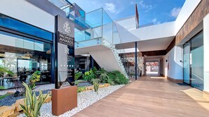 A modern building with a glass facade, a sign for the European Property Awards, and a staircase leading to an upper level. - Ground floor in front of the pool, south facing. (Torre Pacheco)