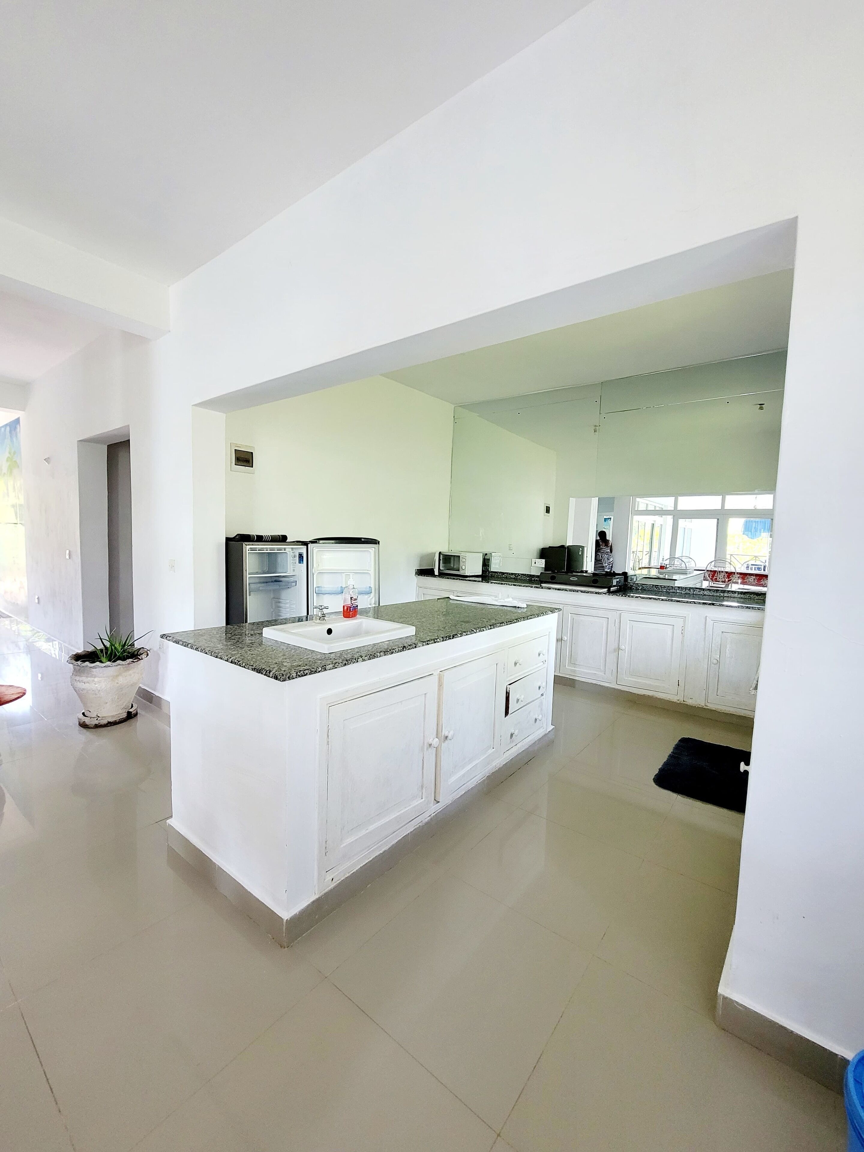 Una cocina amplia con armarios blancos, encimera de granito y una isla central.