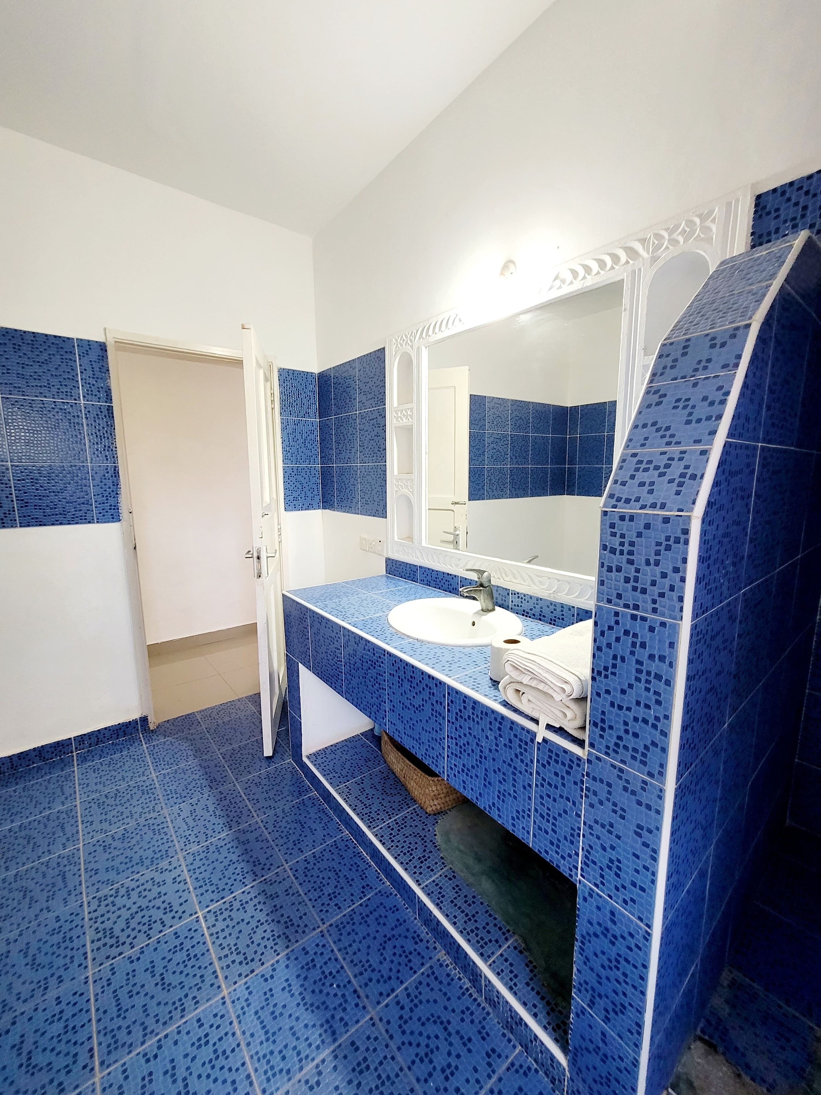 Ein Badezimmer mit blauen Mosaikfliesen, einem weißen Waschbecken und einem Spiegel.