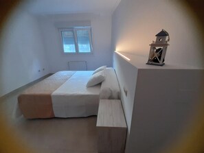 A bedroom with a bed, a nightstand, a window, and a small decorative item on the wall. - APARTAMENTOS COSTAS DE BUEU (Bueu)