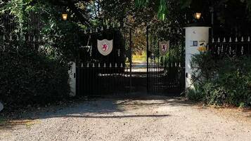 A gated entrance with a coat of arms, a stone sign reading 'Fox House,' and a gravel path leading through.