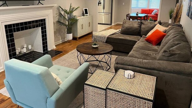 A living room with a fireplace, sofa, armchair, coffee table, and a television. - Rt 66 Retreat - Near Fairgrounds (Tulsa)