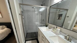 A bathroom with a shower, a sink, and a mirror. - Rt 66 Retreat - Near Fairgrounds (Tulsa)