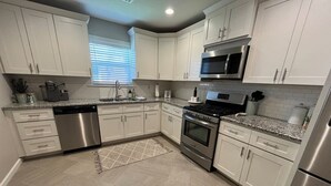 A modern kitchen with white cabinets, stainless steel appliances, and a granite countertop. - Rt 66 Retreat - Near Fairgrounds (Tulsa)