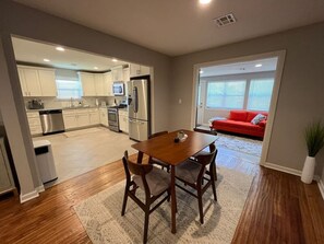 A modern kitchen with white cabinets, stainless steel appliances, and a dining area with a wooden table and chairs.