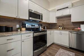 A modern kitchen with white cabinetry, stainless steel appliances, and a granite countertop.