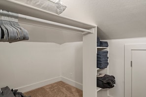 A closet with hanging clothes, folded towels, and a door.
