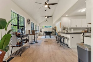 A spacious kitchen with a central island, bar stools, and a dining area with a pool table.