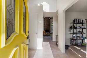 A hallway with a yellow door, a fireplace, and a bookshelf. - Turkey Mountain Trailside by Tulsa Getaways (Tulsa)