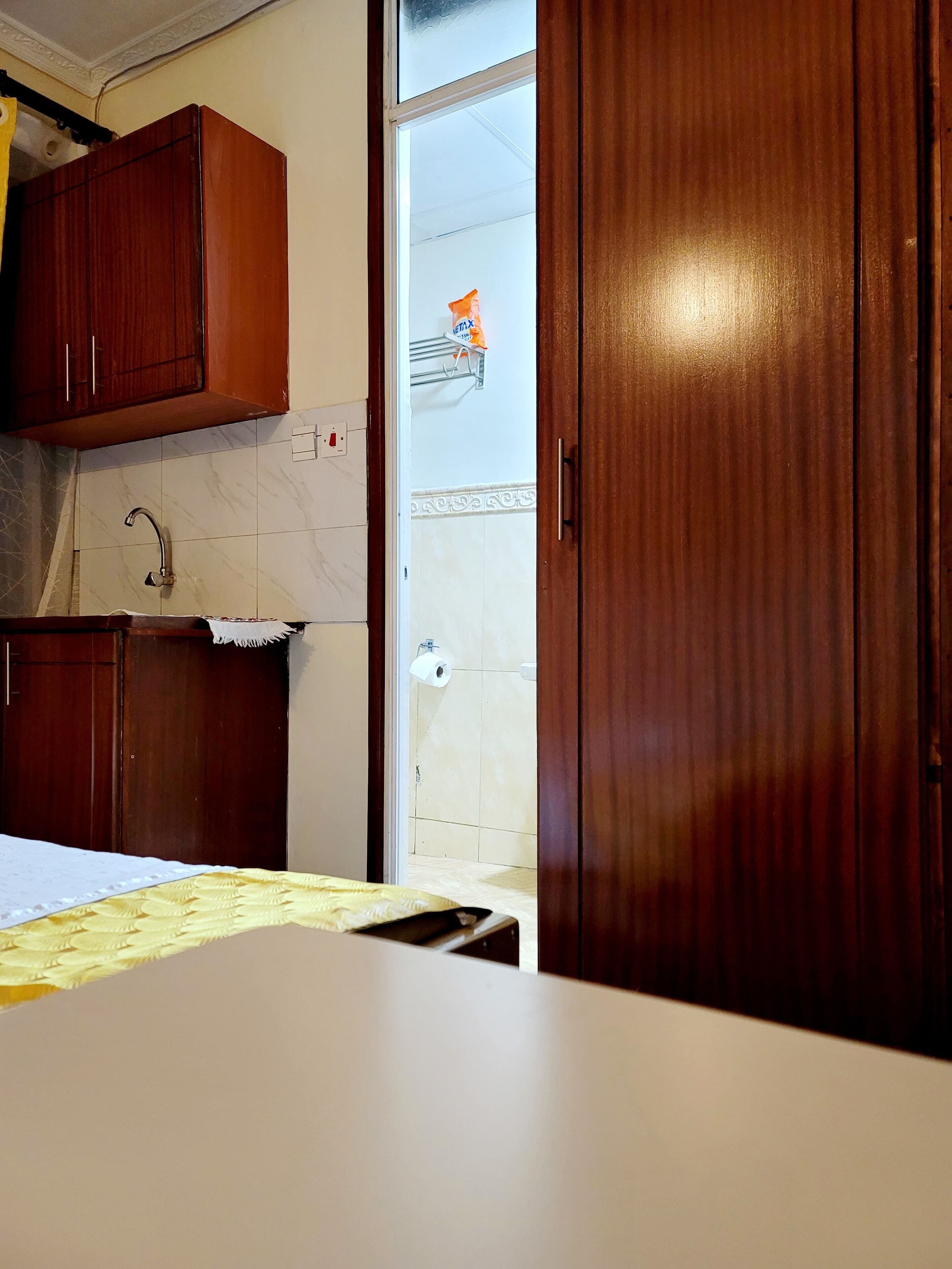 A kitchen with wooden cabinets, a countertop, and a door leading to a bathroom.