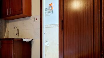 A kitchen with wooden cabinets, a countertop, and a door leading to a bathroom.