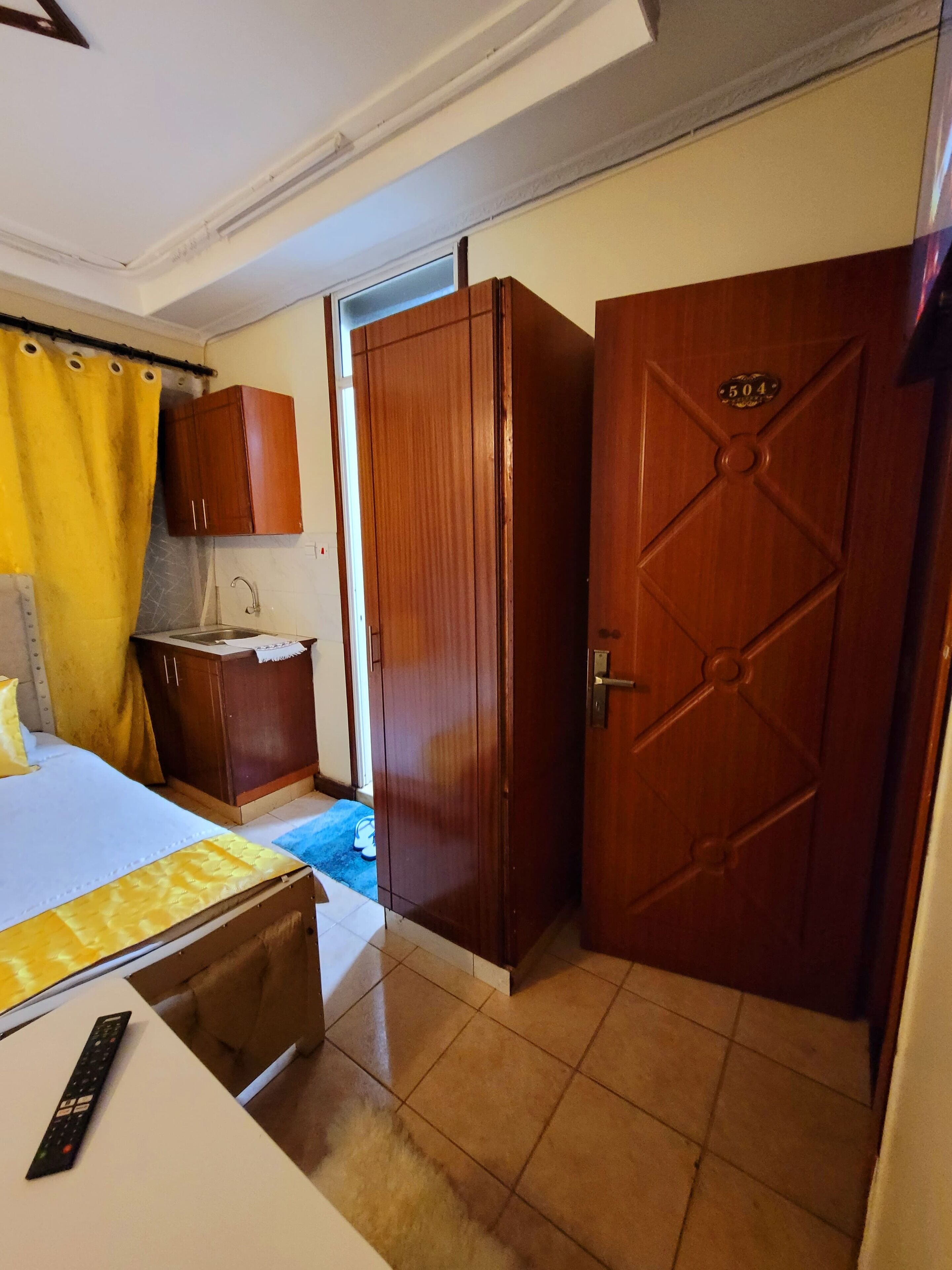 A hotel room with a bed, a desk, a wardrobe, and a bathroom visible through an open door.