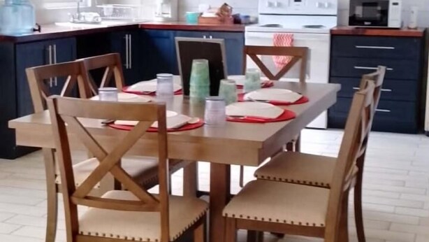 A dining area with a wooden table and chairs, a kitchen in the background, and a window providing natural light. - Nice and Cozy for 6 in Pastores Antigua Guatemala, 8 min from downton Antigua  (Pastores)