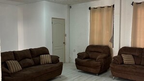 A living room with two brown sofas, a chair, and a door. - Nice and Cozy for 6 in Pastores Antigua Guatemala, 8 min from downton Antigua  (Pastores)