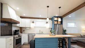 A modern kitchen with white cabinets, a blue island, and pendant lighting.