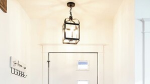 A white door with a black handle, a checkered doormat, and a hanging light fixture above.
