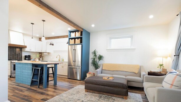 A modern kitchen with a central island, built-in cabinets, and a stainless steel refrigerator.