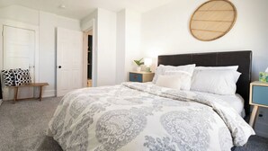 A bedroom with a large bed, a bedside table, a lamp, and a round wall hanging.