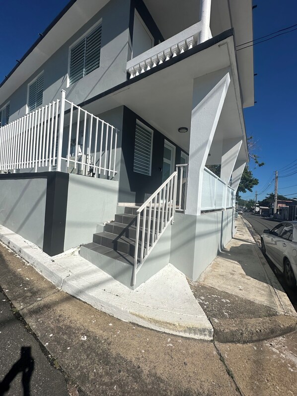 Stylish two-story building with a modern design, featuring a prominent staircase and balcony.