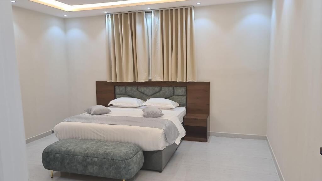 A modern bedroom with a large bed, a nightstand, and a bench.