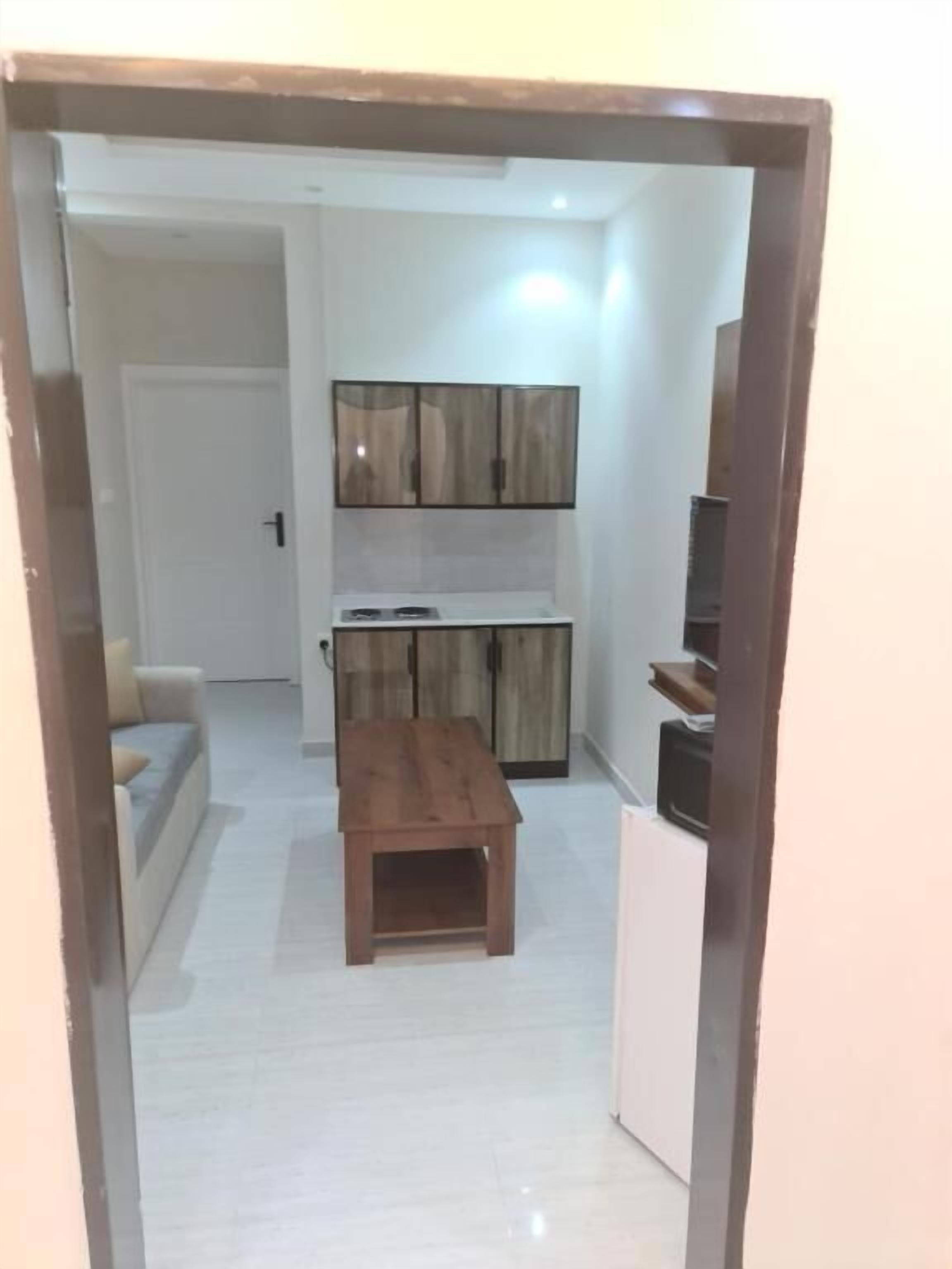 A compact living space with a kitchenette, a wooden table, and a sofa.