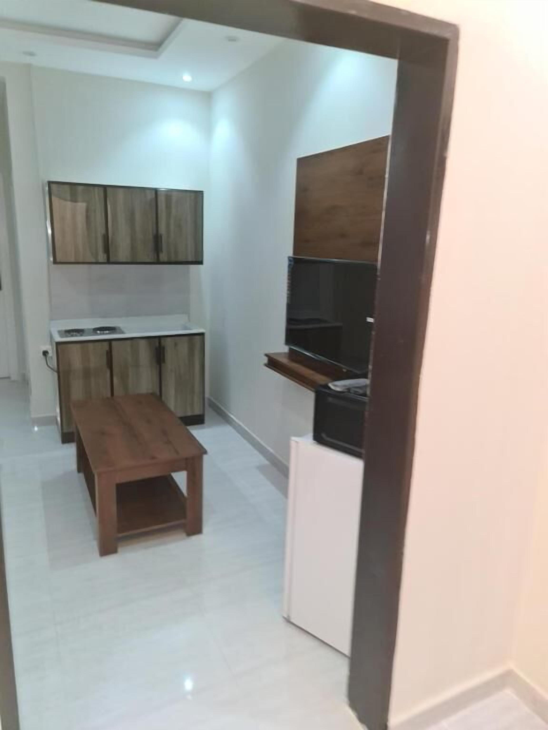 Una cocina funcional con armarios de madera, estufa integrada y una pequeña mesa de comedor.