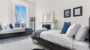 A bedroom with two beds, a fireplace, and a large window. - Upscale Urban Haven: Luxury Flat (London)