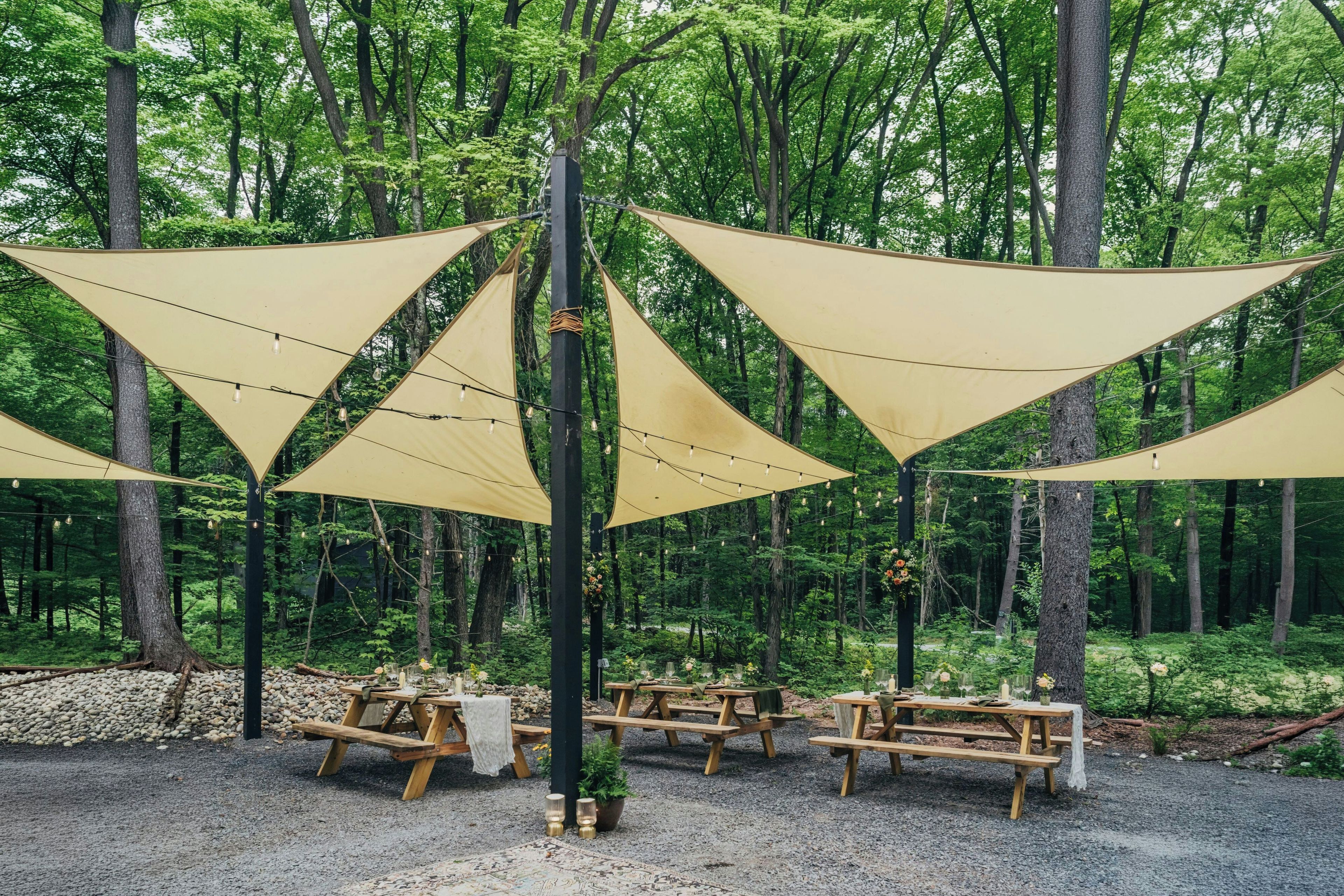 A forested area with picnic tables and triangular shade structures.