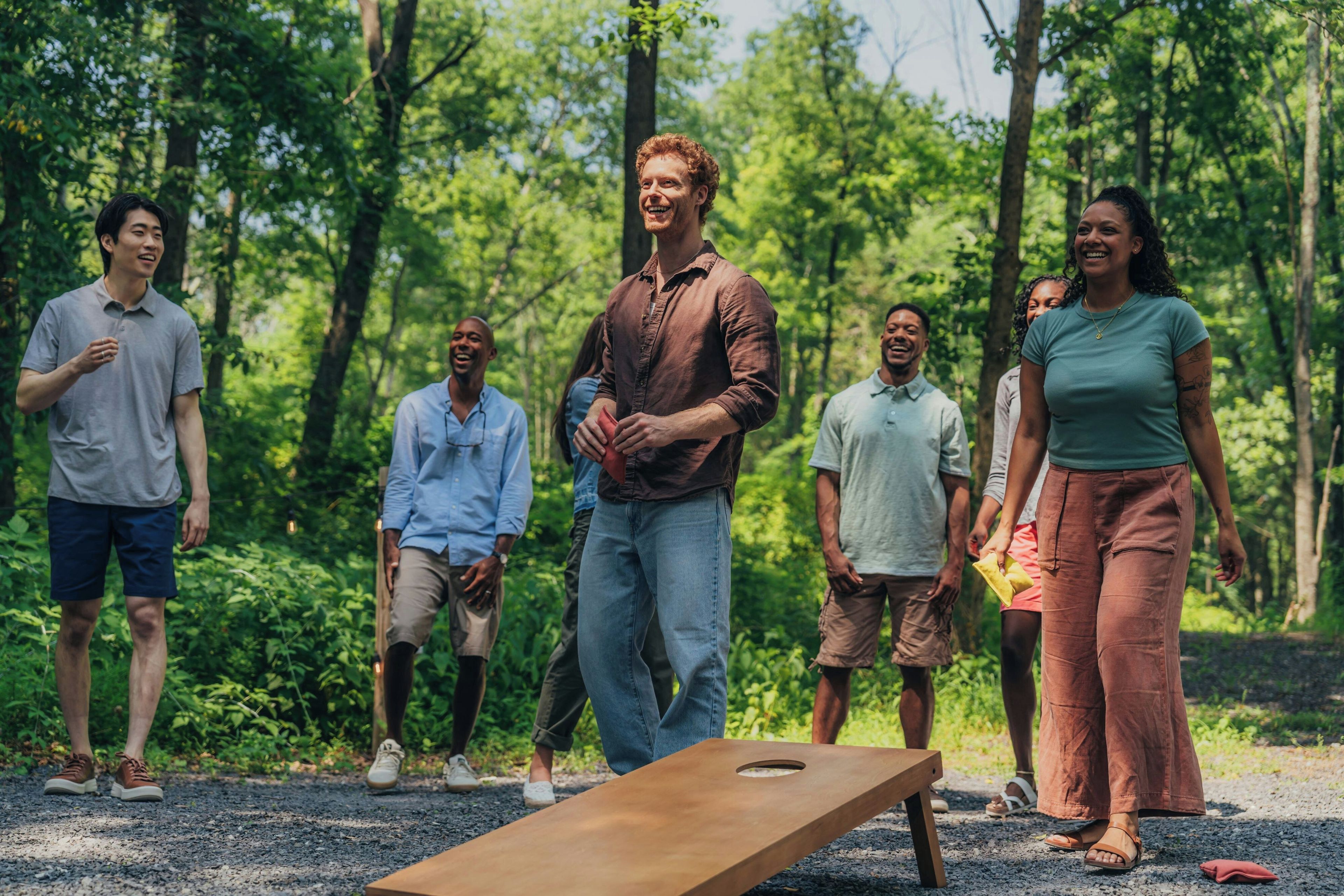 A group of people standing outdoors in a natural setting with trees in the background.