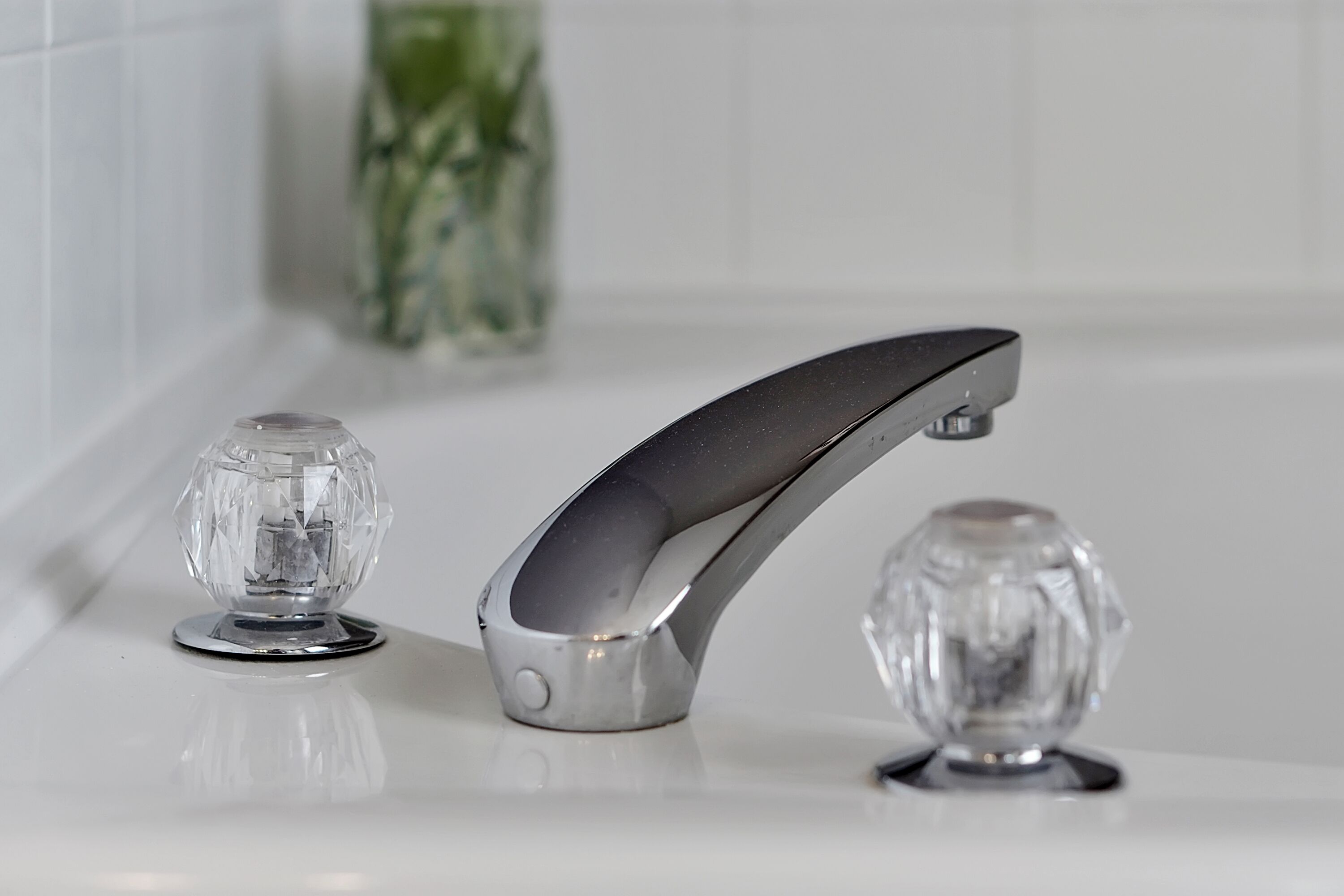 Een moderne badkamer met een strakke, gebogen kraan en twee heldere, decoratieve knoppen op de wastafel.