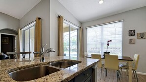 Eine Küche mit Granit Arbeitsplatten, einer Spüle mit zwei Becken und einem Essbereich mit Tisch und Stühlen.