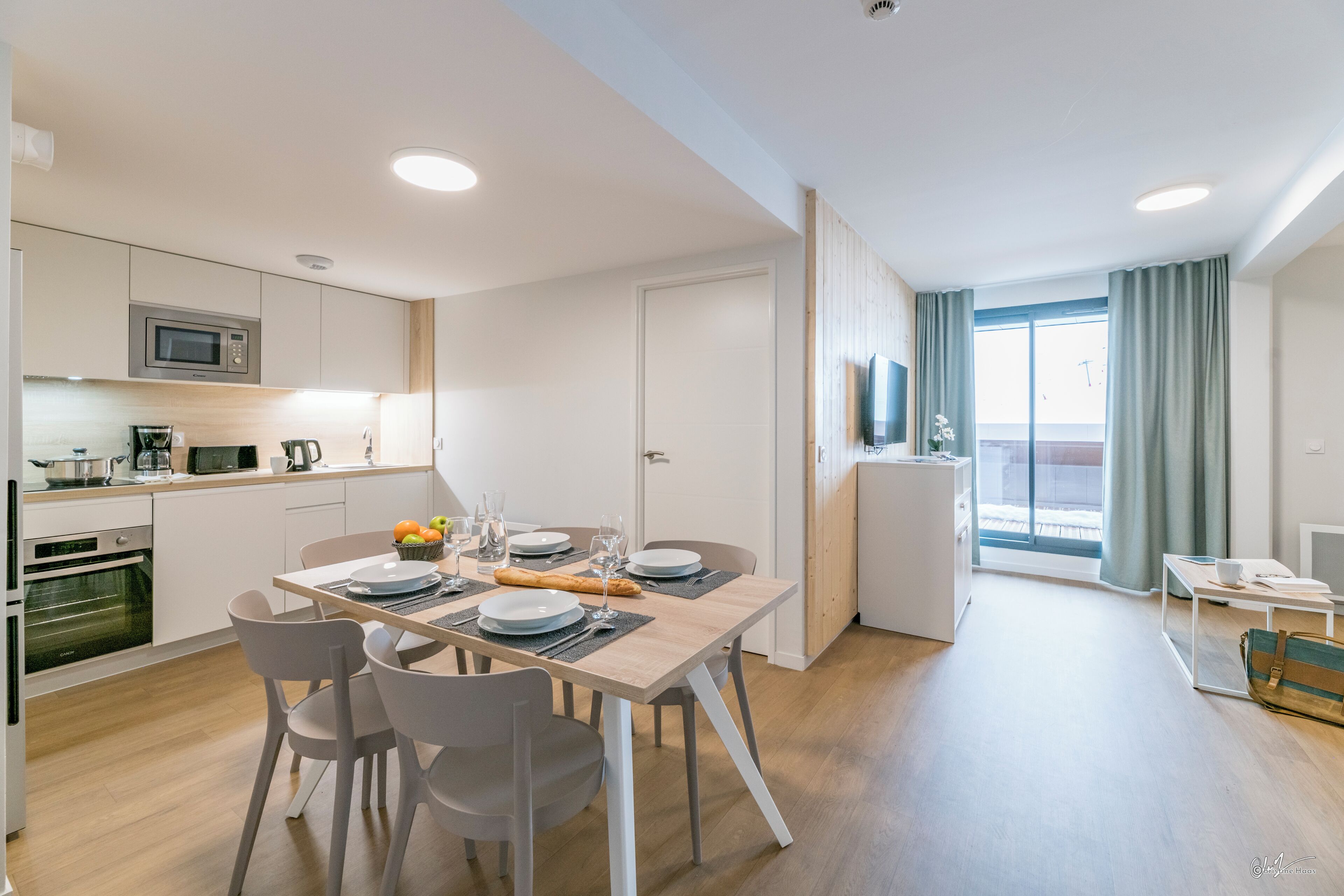 Une cuisine moderne équipée d’un four à micro-ondes, d’un four traditionnel et d’un coin repas avec une table dressée pour deux personnes.