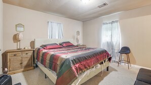 A bedroom with a bed, a nightstand, a dresser, a chair, and a window with curtains. - Hunting & Fishing Retreat in Marvell! (Marvell)