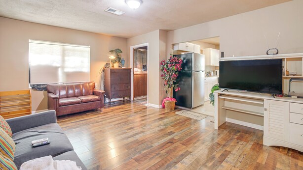 A living room with a sofa, a TV, and a kitchen area in the background. - Hunting & Fishing Retreat in Marvell! (Marvell)