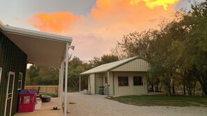 A residential area with a covered garage, a small shed, and a house with a metal roof. - Captain's Cabin on Lake Godstone (Graford)