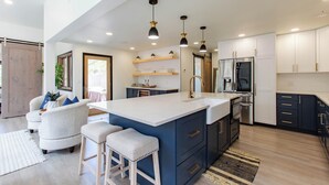 A modern kitchen with a central island, pendant lighting, and built-in appliances.