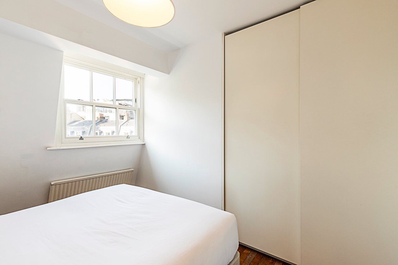 A bedroom with a single bed, a window, and a radiator.